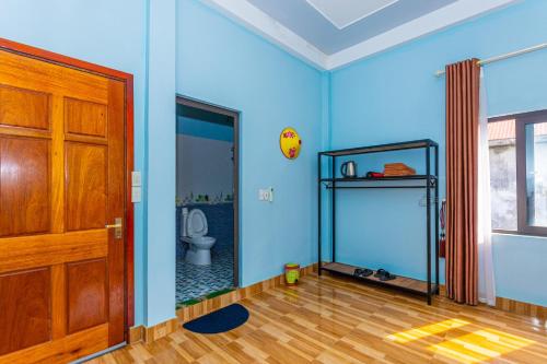 a blue room with a toilet and a wooden door at Son River Homestay in Phong Nha