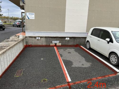 a white car parked in a parking lot next to a building at Quilotoa Mifune Guesthouse in Mifune