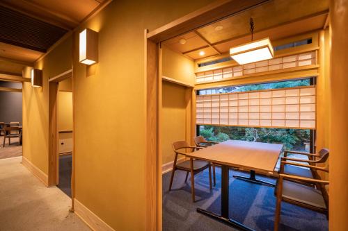 a dining room with a table and a window at Miyajima Grand Hotel Arimoto in Miyajima