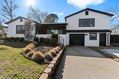 a white house with black windows and a driveway at Villa Bella elegant family retreat in downtown in Bentonville