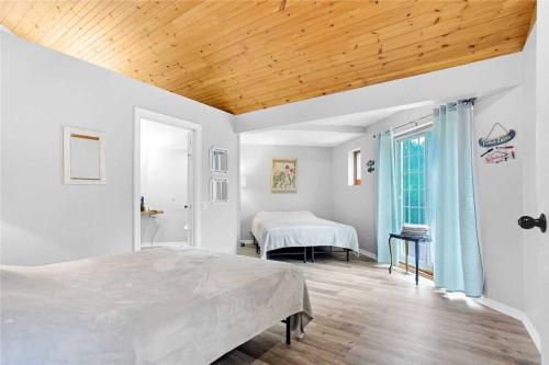 Habitación blanca con cama y ventana en Lovely Muskoka Waterfront Cottage-Hot tub & Sauna!, en Bracebridge