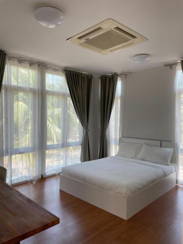 a bedroom with a white bed and windows at San Peak Villa in Sam Roi Yot