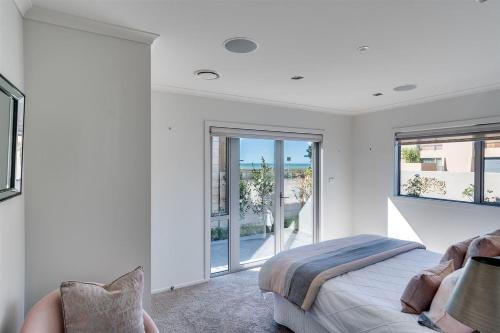 a white bedroom with a bed and a balcony at HotelSuse in Napier