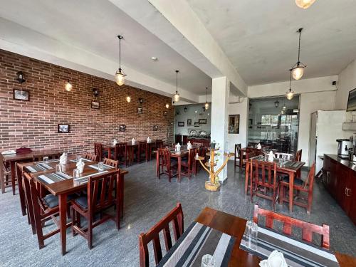 a restaurant with wooden tables and chairs and a brick wall at Royal Pearl Hills in Nuwara Eliya