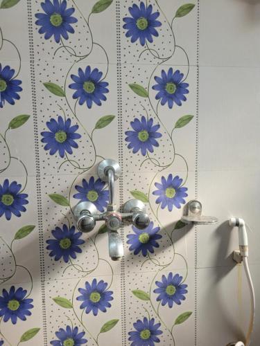 a bathroom with a shower with blue flowers on the wall at Mysa Homestay in Rānchī