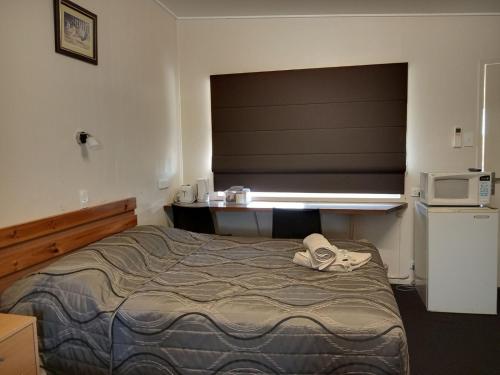 sypialnia z łóżkiem z oknem i kuchenką mikrofalową w obiekcie Three Moon Motel w mieście Monto