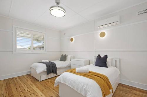 a white room with two beds and a window at Coastal Dreams with Playground & Pets Welcome in Ettalong Beach