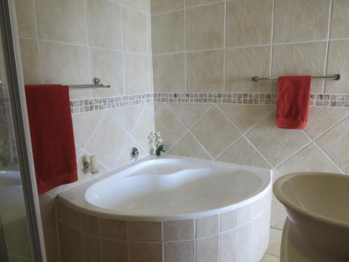 uma banheira branca na casa de banho com toalhas vermelhas em 5 Manaba Breeze em Margate