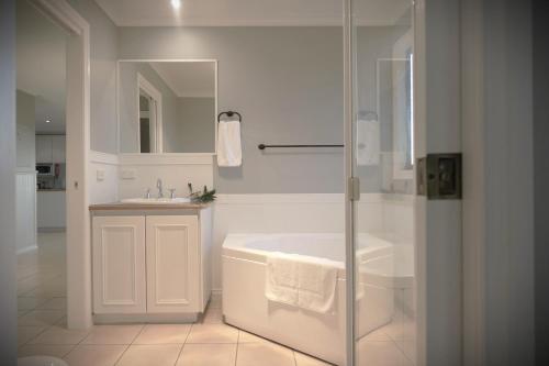 a white bathroom with a tub and a sink at The Roost in Johanna