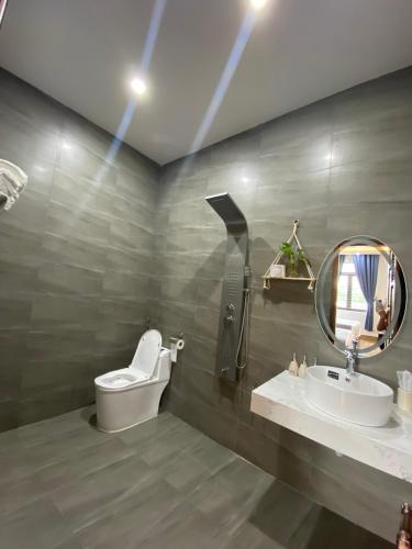a bathroom with a toilet and a sink and a mirror at Hotel Luxstay in Pleiku