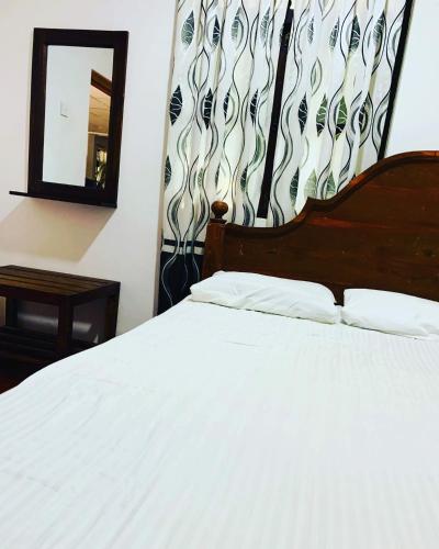 Schlafzimmer mit einem weißen Bett und einem Spiegel in der Unterkunft Thissawewa Guest in Anuradhapura