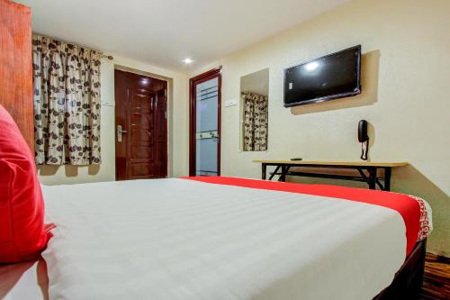 a bedroom with a white bed and a flat screen tv at Super Hotel O Am Grandd in Tiruchchirāppalli