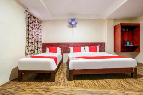 a bedroom with two beds with red and white sheets at Super Hotel O Am Grandd in Tiruchchirāppalli