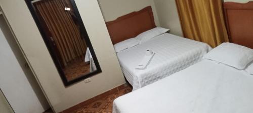 two beds in a hotel room with a mirror at HOSPEDAJE BUENA VISTA in Ayacucho