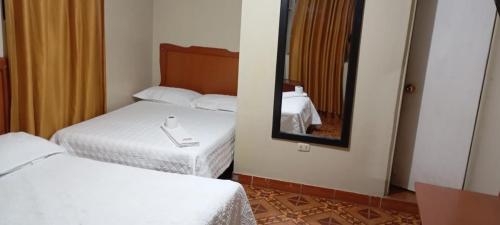 アヤクーチョにあるHOSPEDAJE BUENA VISTAのベッド2台と鏡が備わるホテルルームです。