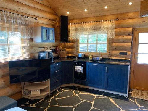 a kitchen with blue cabinets in a log cabin at Russet & Rowanberry - Rowanberry Holiday House in Kriilevälja