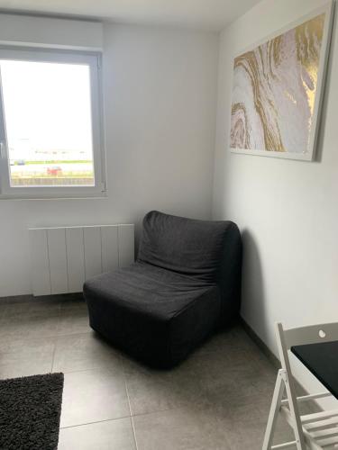 a black bean bag chair in a room with a window at Studio vue sur mer classé 3 étoiles, Calais in Calais