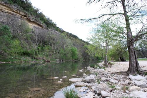 a river with rocks and trees and a mountain at Cliff View #14 in New Braunfels