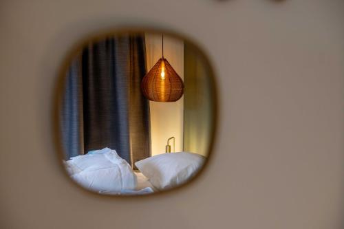 a mirror reflecting a bedroom with two beds and a lamp at De Vlindertuin in Nes