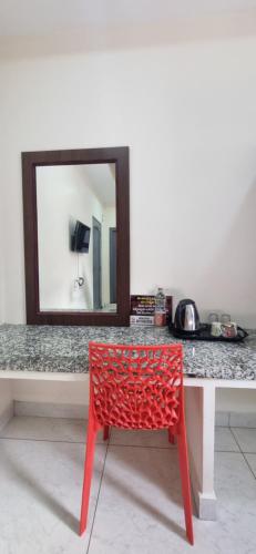 a red chair in front of a table with a mirror at Veda Residency in Machilīpatnam