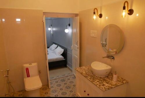 La salle de bains est pourvue d'un lavabo, de toilettes et d'un miroir. dans l'établissement Janki Kunj Varanasi- 3 Room Home, à Varanasi