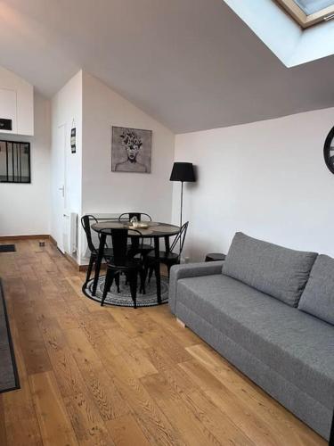 ein Wohnzimmer mit einem Sofa und einem Tisch in der Unterkunft Loft chic climatisé proche château de Vincennes in Montreuil
