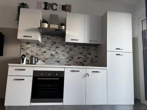 a kitchen with white cabinets and a black oven at ANCORA...IO E TE in Focene