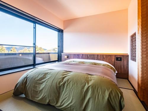 a bedroom with a bed and a large window at Nagominoyado Hanagokoro - Reopening in Mar 2024 in Hakone