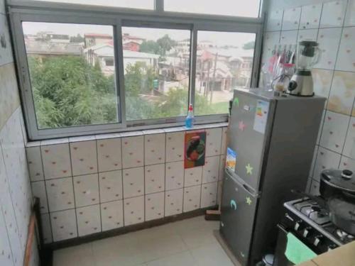 Il comprend une cuisine équipée d'un réfrigérateur et d'une fenêtre. dans l'établissement STUDIO MEUBLE, à Douala