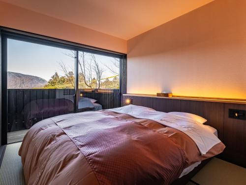 a bedroom with a bed and a large window at Nagominoyado Hanagokoro - Reopening in Mar 2024 in Hakone