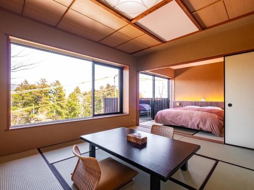 a bedroom with a bed and a table and a window at Nagominoyado Hanagokoro - Reopening in Mar 2024 in Hakone