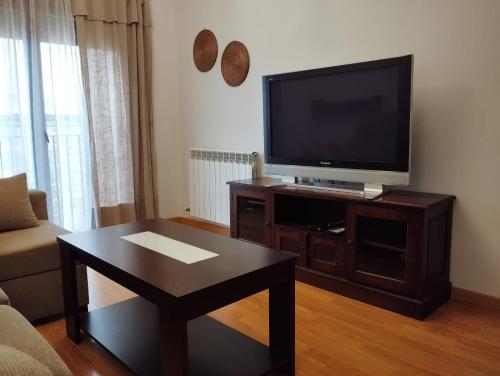 uma sala de estar com uma televisão e uma mesa de centro em Acogedor Apartamento Céntrico em La Puebla de Valverde