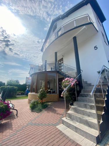 a building with stairs and flowers on a brick patio at Willa Ada Pokoje & Apartamenty in Karwia