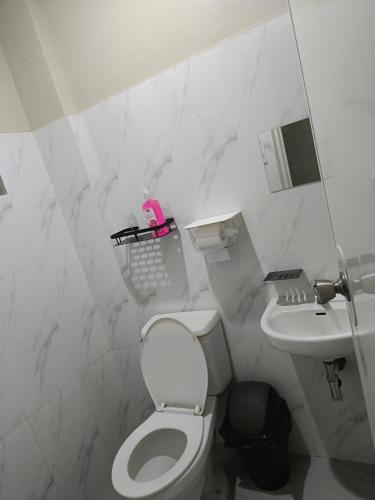 Baño blanco con aseo y lavamanos en Ck building apartment, en Mabalacat