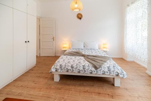a white bedroom with a bed and two lamps at Apartments house Pinezic in Malinska
