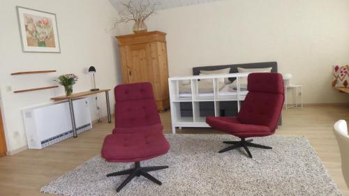 two red chairs in a room with a bed at Landleben in Fritzlar