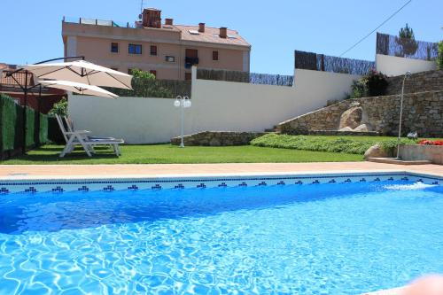a swimming pool with an umbrella and a house at Apartamentos Maritimo Suites-Solo Adultos in O Grove