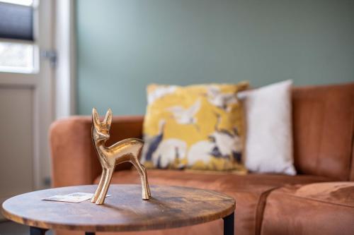 a small gold figurine on a table in front of a couch at De Vlindertuin in Nes