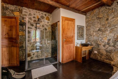 a bathroom with a shower and a stone wall at Jml villa foresta in Kalawana