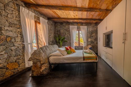 1 dormitorio con 1 cama en una pared de piedra en Jml villa foresta en Kalawana