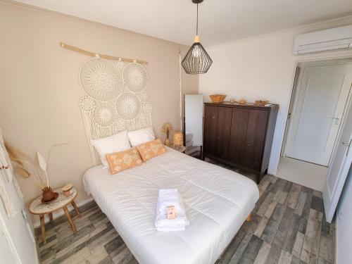 een slaapkamer met een wit bed met een houten hoofdeinde bij T3 De Charme - avec clim, parking et piscine in Le Lavandou