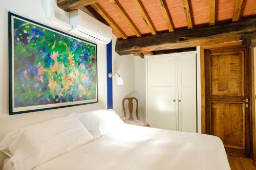 a bedroom with a white bed and a painting on the wall at Podere Campriano Winery Adult only in Greve in Chianti