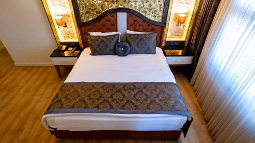 a bedroom with a large bed with a large headboard at Can Adalya Palace Hotel in Antalya