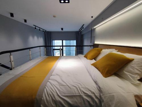 a large white bed with yellow pillows in a room at Panda ZuoKe Besucher Apartment 熊猫坐客民宿 in Kunming