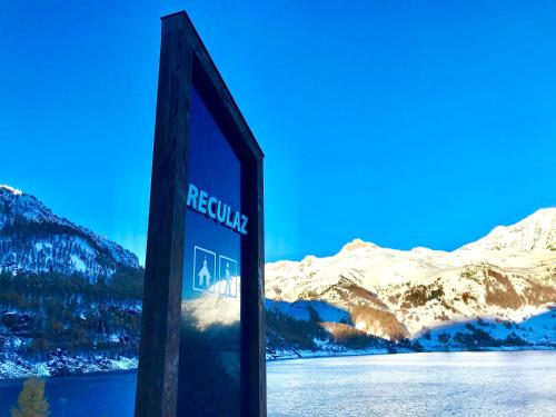 ein Schild vor einem See und verschneiten Bergen in der Unterkunft Chalet 1728 - La Reculaz - 2 minutes from Val D'isere in Tignes