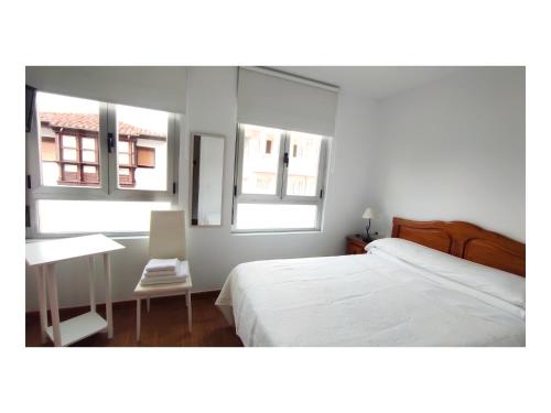 a bedroom with a bed and a desk and two windows at Pension Villa ** in Comillas