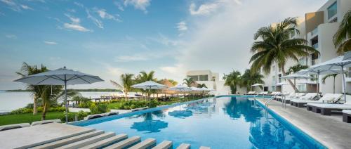 uma piscina no resort com cadeiras e guarda-sóis em Real Inn Cancún em Cancún