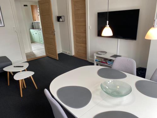 een kamer met een witte tafel en stoelen en een televisie bij Siesta Vejle in Vejle