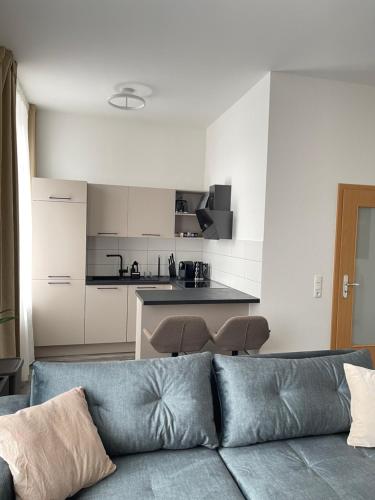a living room with a couch and a kitchen at Moderne und stilvolle Wohnung direkt am Teich in Altenburg