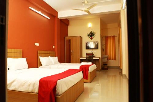 two beds in a hotel room with red walls at Karamangattu Residency in Ramakkalmedu